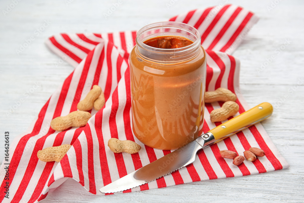 Jar with creamy peanut butter on table