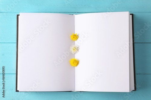 Fotografía Open book with blank pages and beautiful flowers on color wooden background, clo