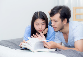 Couple reading a book together in bedroom on the morning with happiness.