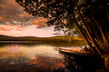 Canoe On The Lake At Sunset. Warm Sunset Colors Spill Over Mongaup Pond, The Largest Lake In The Catskills. One Of The Most Popular Summer Vacation And Camping Destination In New York