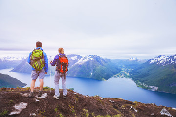 couple of hikers on top of the mountain, group of backpackers traveling in Norway fjords, people looking at beautiful panoramic landscape