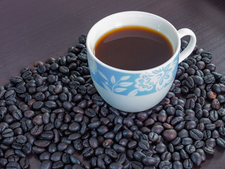 Coffee in cup with coffee beans around.