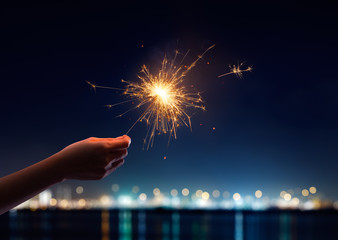 Wall Mural - Female hand holding a burning sparkler