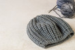 © elizaveta66 - Hobby of manual knitting. A warm gray hat, balls wool fluffy yarn and knitting needles on a light background.