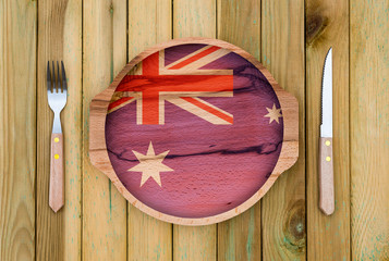 Wall Mural - Concept of Australian cuisine. Wooden plate with a Australia flag , fork and knife on a wooden background