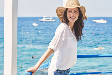 Canvas Print - Young beautiful woman in a straw hat resting by the sea