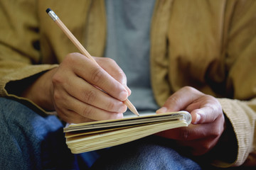 Man hand with pencil writing on notebook.