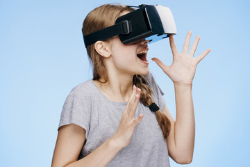 Young beautiful woman on a blue background with virtual reality glasses