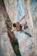 © Александра Голубцова - sports man climbs an overhang rock near forest and put his hand into magnesia bag