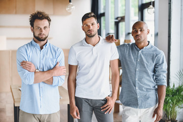 Wall Mural - multiethnic young businessmen looking at camera while standing in office