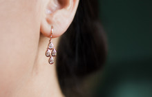 Rose Gold Earring Hangs In Caucasian Brunette Woman's Ear