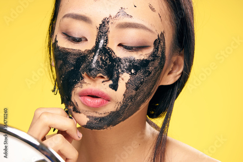 Young Beautiful Woman On Yellow Background Black Coal Cosmetic Face Mask Asian Buy This Stock Photo And Explore Similar Images At Adobe Stock Adobe Stock