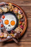 Fototapeta Natura - Fried eggs in the shape of a skull and fresh tomatoes. Breakfast in Halloween decorations.