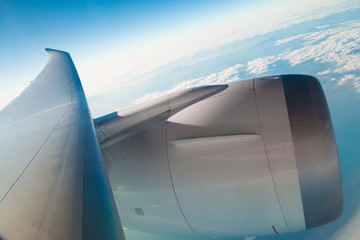 air plane engine and wing floating over white cloud and blue sky use as background,backdrop