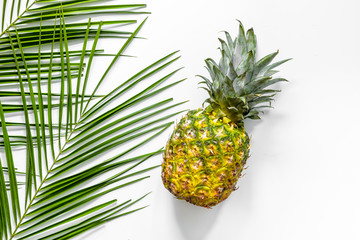  Pineapple and palm branch on white background top view copyspace