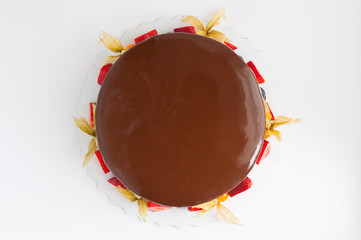 Birthday cake in chocolate with strawberries, blueberries and physalis on white background. Top view. Picture for a menu or a confectionery catalog.