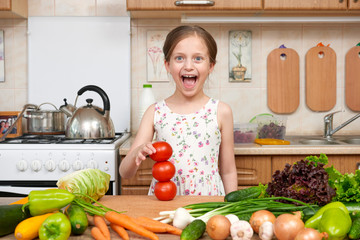 Child girl having fun with tomatoes. Home kitchen interior with fruits and vegetables. Healthy food concept