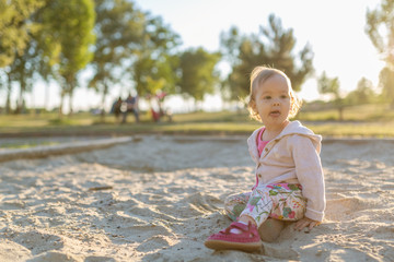 Wall Mural - Fifteen months old baby girl playing in the sandbox in the sunset