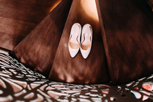 Peach Bridal Wedding Shoes On Wooden Stairs With Decorative Railings