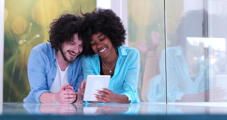 Wall Mural - Couple relaxing together at home with tablet computer