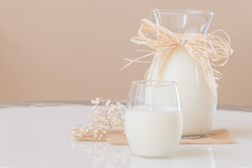 A glass of milk and a pitcher of milk on marble table.