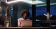 © .shock - black businesswoman using a laptop in night startup office