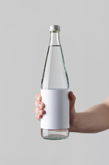 Wall Mural - Water Bottle Mock-Up. Blank Label - Male hands holding a water bottle on a gray background