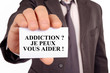 © Richard Villalon - Homme tenant une carte avec addiction je peux vous aider écrit dessus