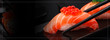 Japanese cuisine. Salmon sushi nigiri in chopsticks over black background.