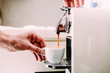 The man is holding a white cup. Close-up, coffee preparation by a professional coffee machine