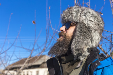 Wall Mural - Closeup portrait of a bearded young man with fur cap and sunglasses