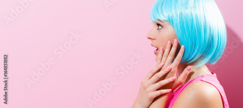 Portrait of a woman in a bright blue wig on a pink background