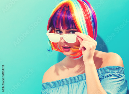 Beautiful woman in a colorful wig on a blue background