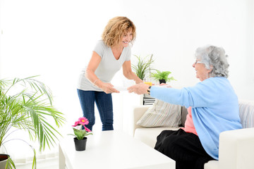 Wall Mural - cheerful mature woman serving breakfast and taking care of elderly senior woman at home