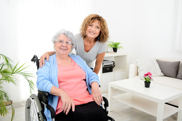 Wall Mural - cheerful mature woman visiting retirement home residence with elderly senior woman on wheelchair