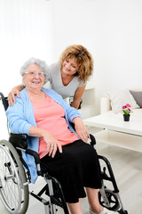 Wall Mural - cheerful mature woman visiting retirement home residence with elderly senior woman on wheelchair