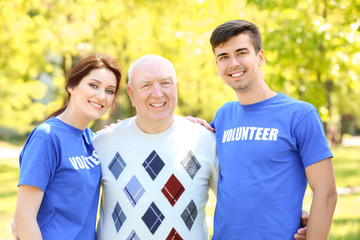 Wall Mural - Happy senior man and young volunteers outdoors on sunny day