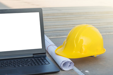 Wall Mural - The safety helmet and the blueprint with laptop has white screen isolated at construction site