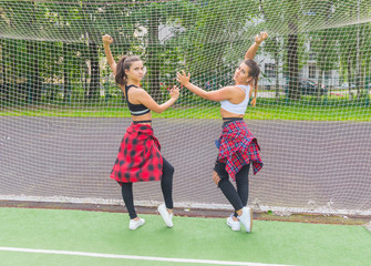 two sporty girls posing at a football grid on the Playground.