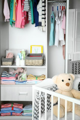 Wall Mural - Crib and wardrobe with clothes in light baby room