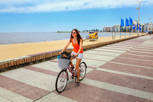Woman Biking On The Boulevard Along Pocitos Beach In Montevideo, Uruguay.