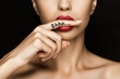 cropped view of seductive woman with red lips showing shh symbol, isolated on black