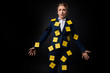overworked middle aged businesswoman standing with sticky notes on suit isolated on black