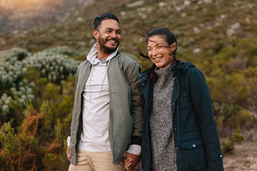 Wall Mural - Smiling young couple walking in the countryside