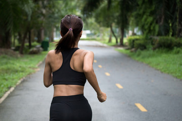 Wall Mural - Young fitness sport woman running on the road in the morning, Selective focus