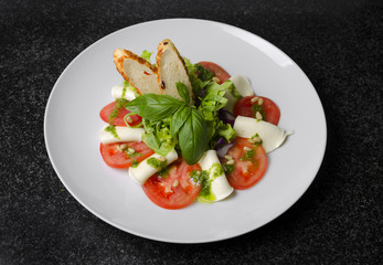 Wall Mural - Salad with tomatoes basil and mozzarella with croutons on a white plate