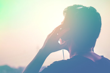 Man silhouette listening to the headphones on the sunset landscape background, Soft and sweet tone