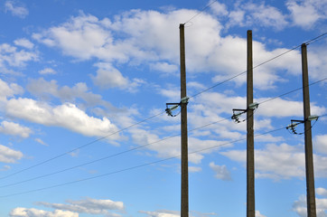 Concrete pole with wires of power line against the background of blue cloudy sky