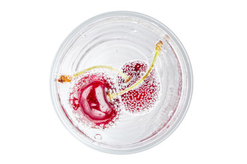 Top view of sweet shiny cherry in soda water with bubbles of carbon dioxide on white background.