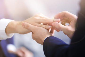 One groom placing the ring on another man's finger